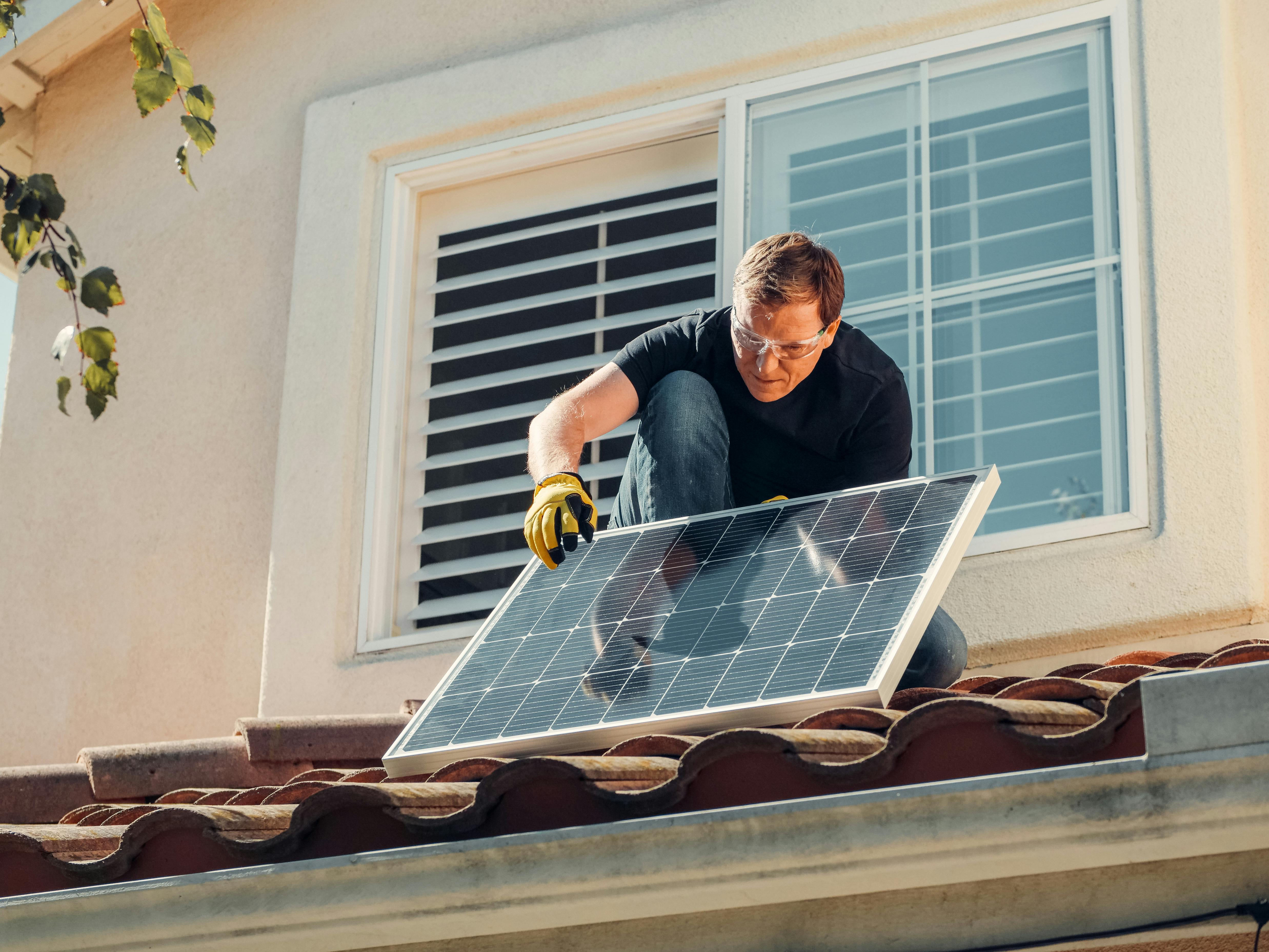 Man fitting a solar panel on a roof